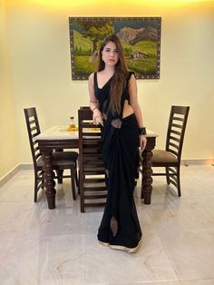 a woman standing in front of a table wearing a black sari