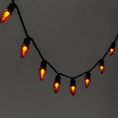 a string of christmas lights hanging from a wire on a gray wall with no one in the photo