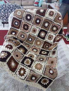 a crocheted blanket sitting on top of a chair in front of a couch