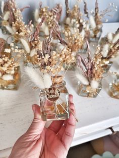 a person holding a glass jar with dried flowers in it