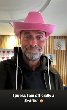 a man wearing a pink cowboy hat with the caption i guess i am officially a'swiftie '