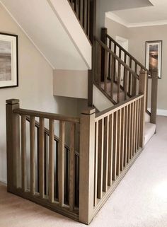 an empty room with some stairs and pictures on the wall above it, along with carpeted flooring