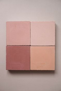 four different colored blocks are arranged on a white wall, one is pink and the other is beige