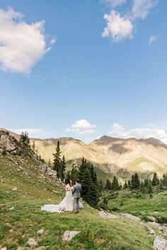 a bride and groom standing on top of a mountain