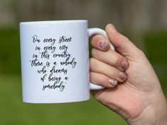 a woman holding a coffee mug with writing on it's side and her hand in the air