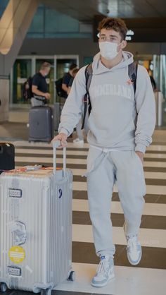 a man with a face mask is pulling a suitcase