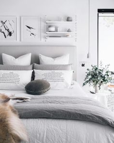 a bed with white sheets, pillows and pictures on the wall above it in a bedroom