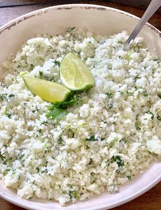 a white bowl filled with rice and lime wedges