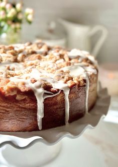 a close up of a cake on a plate with icing and flowers in the background