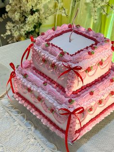 three tiered cake sitting on top of a table with red ribbon around the edges