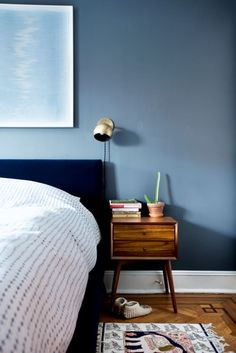 a bedroom with a bed, nightstand and painting on the wall