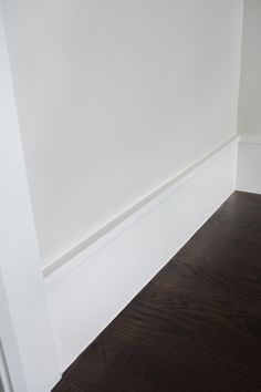 the corner of a room with white walls and wood flooring is painted in dark brown