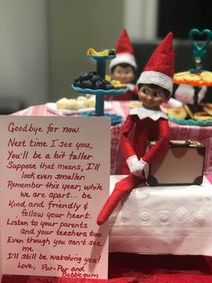 an elf sitting on top of a table next to a sign