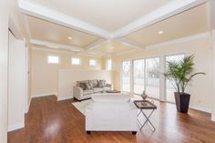 a living room with hard wood floors and white furniture