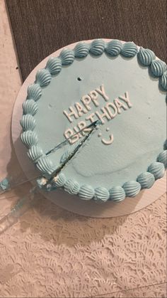 a blue birthday cake with the words happy birthday on it sitting on a lace tablecloth