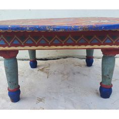 an old bench is painted with blue, red and gold paint on it's legs