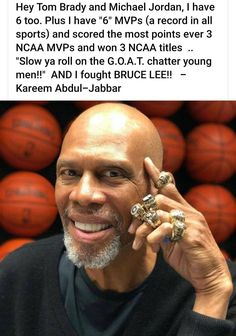 the man is talking on his cell phone in front of some basketballs and smiles