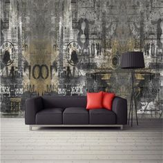 a couch sitting in front of a wall with clocks on it's side and a lamp next to it