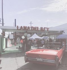 an old red car parked in front of a market