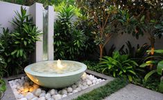 a bowl shaped fountain surrounded by rocks and greenery