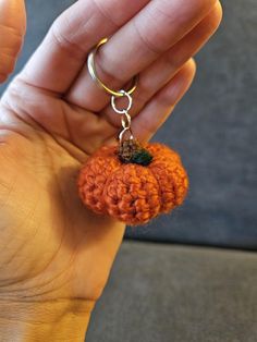 a hand holding a tiny crocheted pumpkin keychain