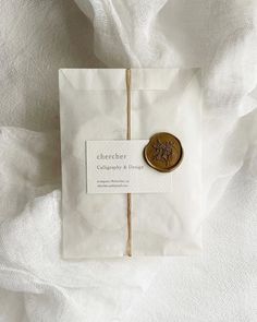 a paper bag with a badge on it sitting on top of a white cloth covered bed