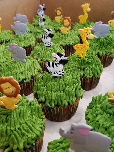 cupcakes with green frosting and jungle animals on them are ready to be eaten