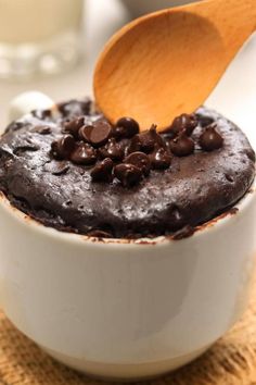 a wooden spoon in a white bowl filled with chocolate cake