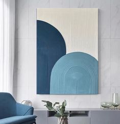 a living room scene with focus on the blue chair and wall art above the coffee table