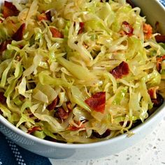 a bowl filled with coleslaw and bacon on top of a blue table cloth