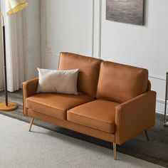 a tan leather couch sitting on top of a white rug