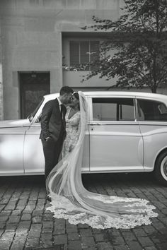 a bride and groom kissing in front of an old car