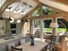 an open kitchen and dining room area with wooden beams on the ceiling, glass doors leading outside