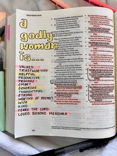 an open bible with the words godly woman written on it next to pens and markers