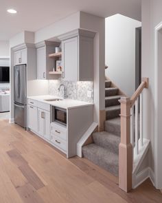 a kitchen with white cabinets and gray stairs