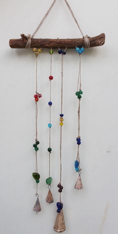 a wind chime hanging on a wall with beads and wood sticks attached to it