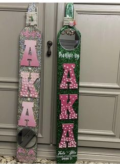 two snowboards are decorated with pink and green glitter letters that spell out the word alaska