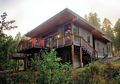 a wooden house sitting on top of a hill surrounded by trees and bushes in the woods