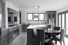 a large kitchen with an island table surrounded by gray cabinets and counter tops, along with glass doors leading to the outside