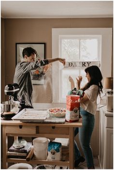 a man and woman are in the kitchen preparing food together, with one person reaching for something