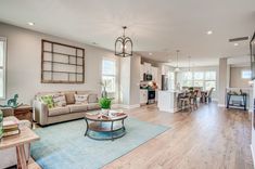 a living room filled with furniture next to a kitchen and dining room table on top of a hard wood floor