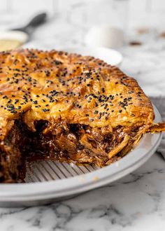 a meat pie on a plate with one slice cut out and ready to be eaten