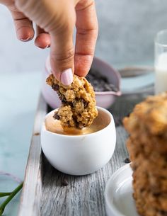 a person dipping something into a small bowl with some oatmeal in it