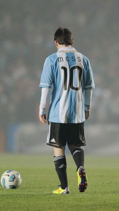 a soccer player is standing on the field with his foot in front of a soccer ball