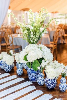 blue and white vases filled with flowers on top of a wooden table covered in tables cloths