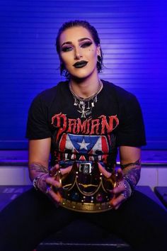 a woman with black makeup and piercings sitting on a bench holding a trophy in her hands