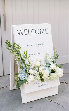 a welcome sign with white flowers and greenery