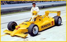 a man sitting on top of a yellow race car