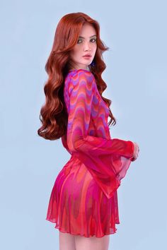 a woman with long red hair wearing a pink and purple dress is posing for the camera