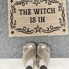 someone standing in front of a door mat that says the witch is in